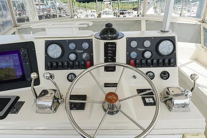 Impulse Yacht Photos Pics 1987 Viking Palm Beach yacht helm with steering wheel, gauges, and navigation controls.