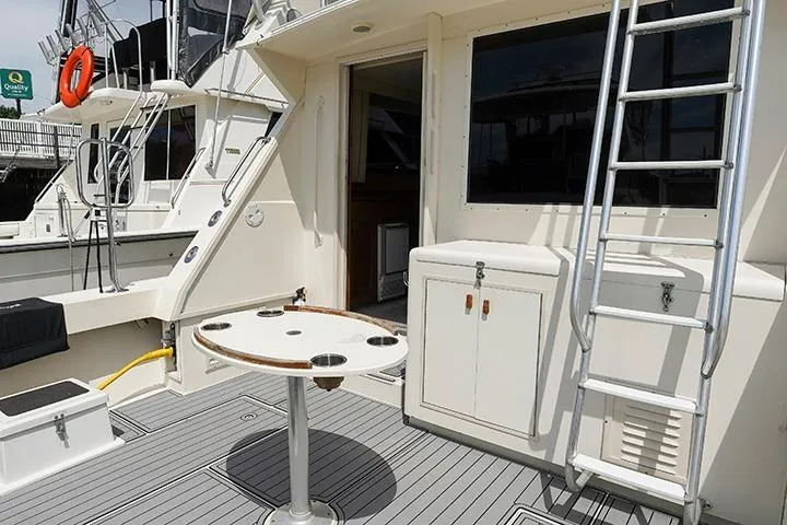 Impulse Yacht Photos Pics 1987 Viking Palm Beach yacht deck with table, ladder, and storage cabinet.