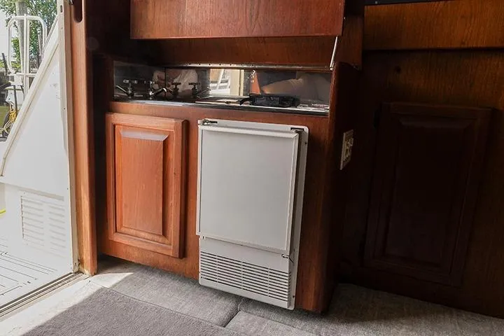 Impulse Yacht Photos Pics 1987 Viking Palm Beach yacht interior with wooden cabinetry and compact refrigerator.