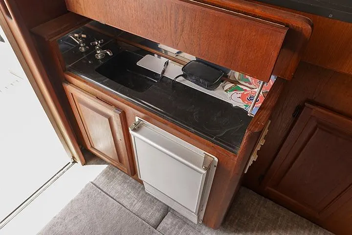 Impulse Yacht Photos Pics 1987 Viking Palm Beach yacht interior with wooden cabinetry and compact kitchenette.