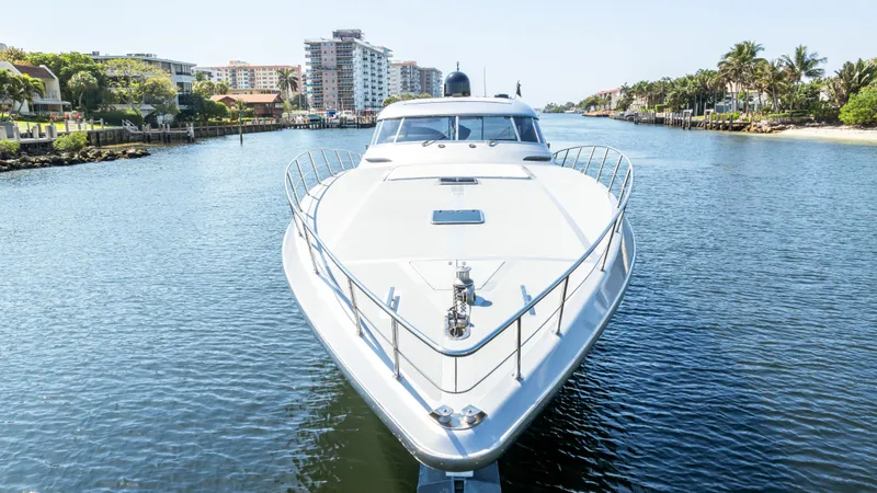 Alchemy Yacht Photos Pics Luxury 2003 Baia Panther 80 yacht on a serene waterway, surrounded by urban and natural scenery.