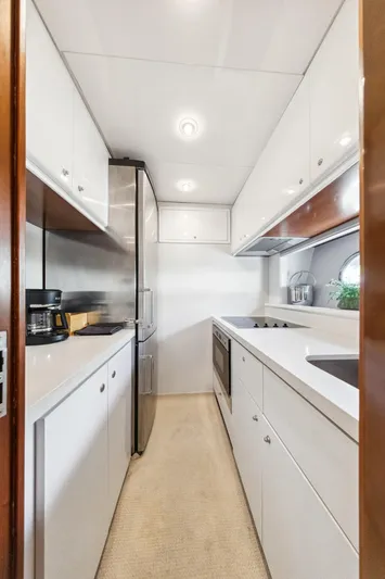 Alchemy Yacht Photos Pics Modern kitchen interior on 2003 Baia PANTHER 80 yacht, featuring sleek white cabinetry and stainless steel appliances.