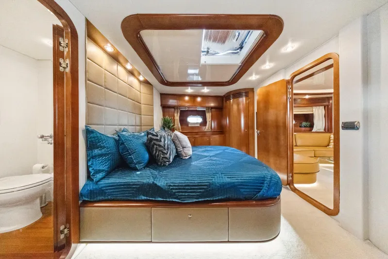 Alchemy Yacht Photos Pics Luxurious 2003 Baia Panther 80 yacht bedroom with blue bedding and elegant wood accents.