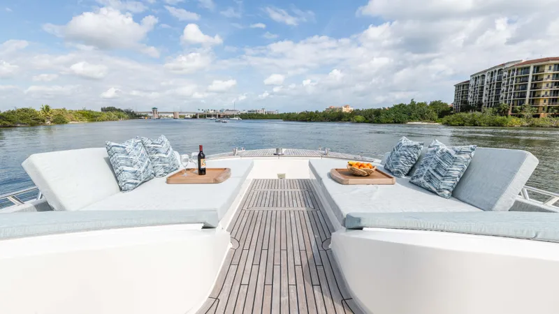 Nauti Style Yacht Photos Pics Luxurious Monte Carlo Yachts MCY 65 deck with cushions, wine, and fruit, overlooking serene waters.