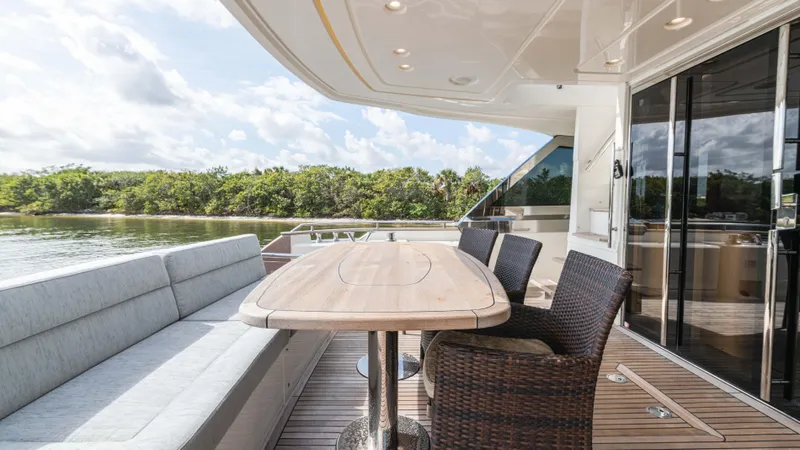 Nauti Style Yacht Photos Pics Luxury outdoor seating on 2016 Monte Carlo Yachts MCY 65, featuring elegant wicker chairs and wooden table.