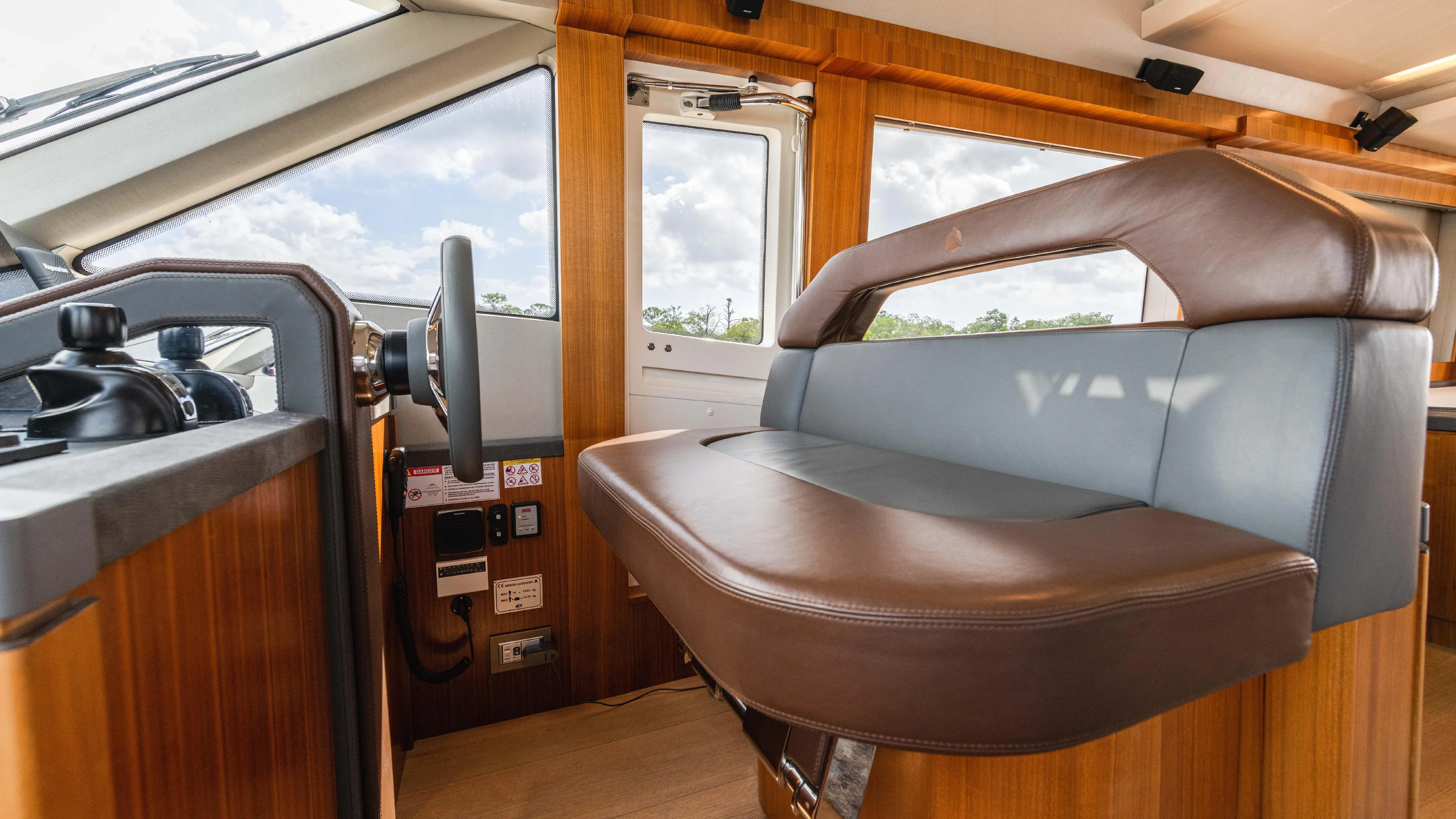 Nauti Style Yacht Photos Pics Interior helm of 2016 Monte Carlo Yachts MCY 65 with leather seating and wooden accents.
