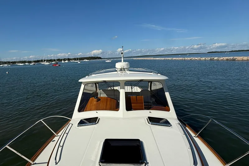Sterling Yacht Photos Pics 2024 Hinckley Picnic Boat 40 S cruising on a serene lake under a clear blue sky.