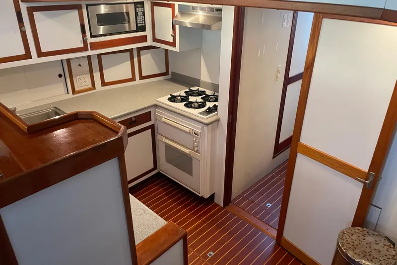  Yacht Photos Pics 1969 Islander 72 Aft Cabin Motor Yacht kitchen with stove, microwave, and wood accents.
