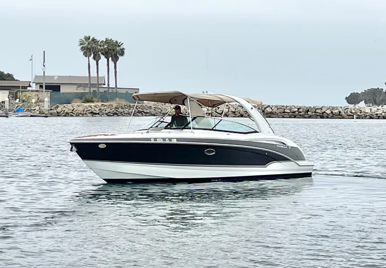  Yacht Photos Pics 2009 Formula 310 BR boat cruising on calm water near a rocky shoreline.