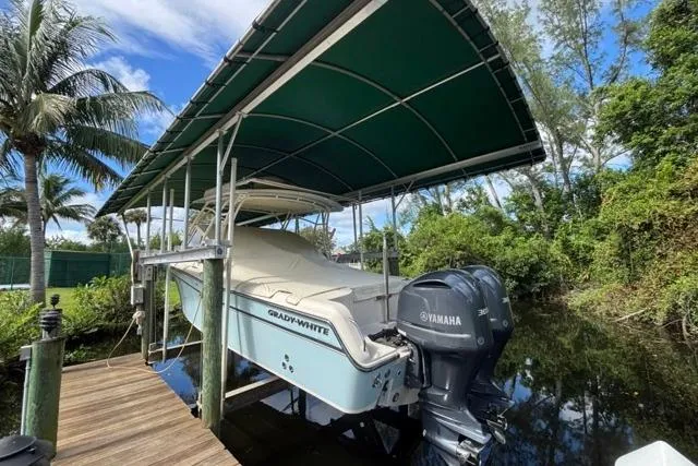  Yacht Photos Pics 2019 Grady-White Freedom 285 boat with Yamaha engine under canopy, docked near lush greenery.