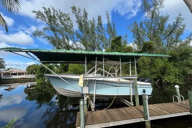  Yacht Photos Pics 2019 Grady-White Freedom 285 boat on lift, surrounded by lush greenery and calm water.