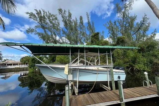  Yacht Photos Pics 2019 Grady-White Freedom 285 boat docked under a canopy, surrounded by lush greenery.