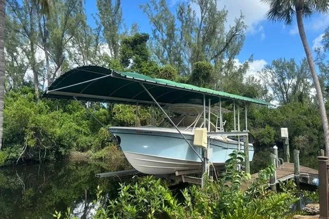  Yacht Photos Pics 2019 Grady-White Freedom 285 boat on lift, surrounded by lush greenery and blue sky.