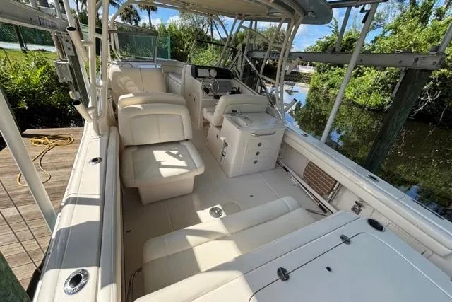  Yacht Photos Pics 2019 Grady-White Freedom 285 boat interior with seating and helm, docked by lush greenery.