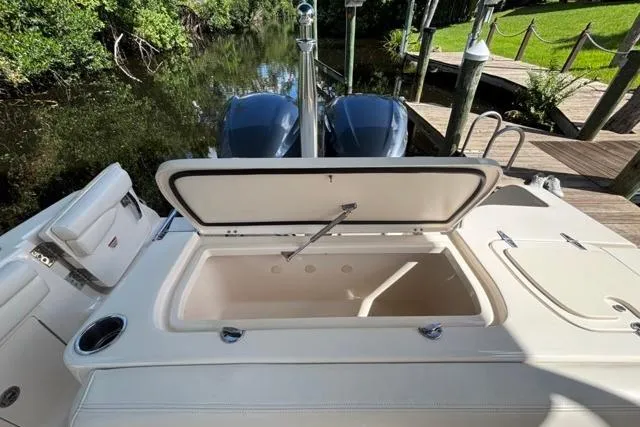  Yacht Photos Pics 2019 Grady-White Freedom 285 boat with open storage compartment, docked by a lush riverside.