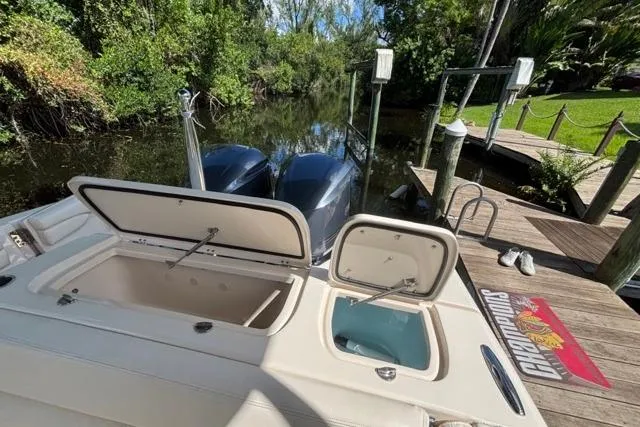  Yacht Photos Pics 2019 Grady-White Freedom 285 boat with open storage compartments, docked by a lush riverside.