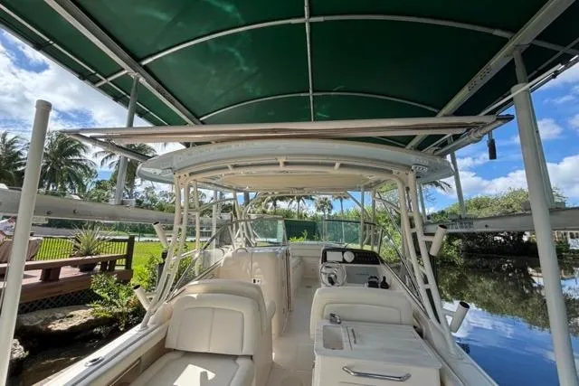  Yacht Photos Pics 2019 Grady-White Freedom 285 boat with green canopy, docked near lush greenery.