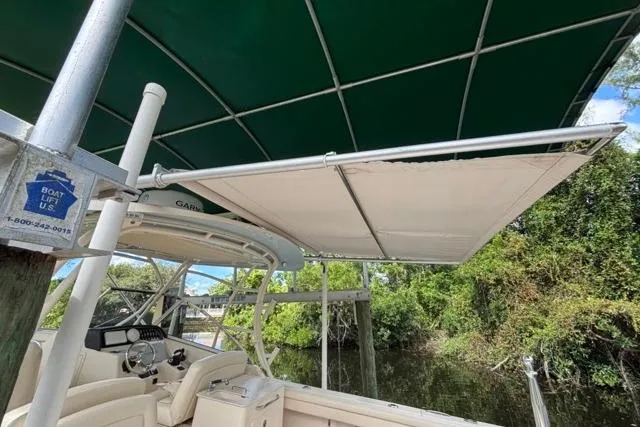  Yacht Photos Pics 2019 Grady-White Freedom 285 boat with canopy, docked near lush greenery.