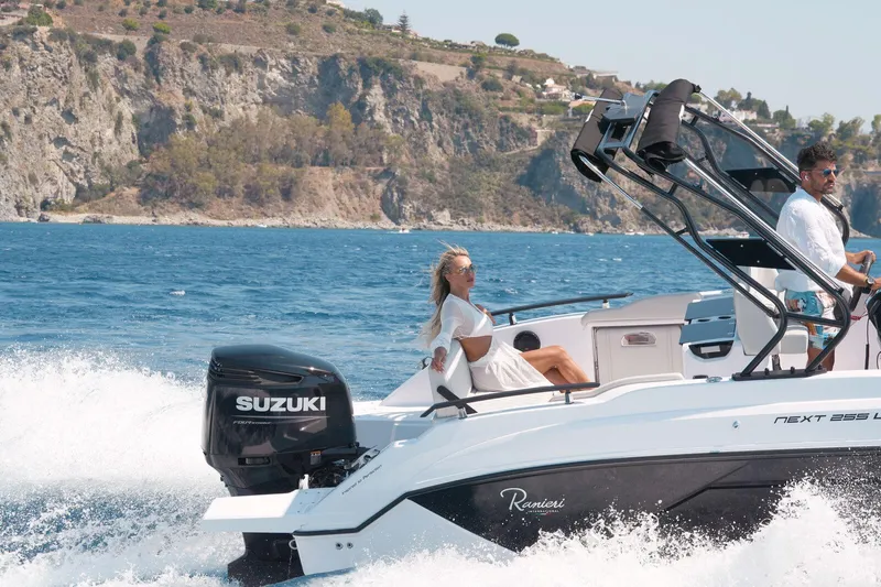  Yacht Photos Pics 2025 Ranieri NEXT 255 LX boat cruising on blue water near rocky coastline.