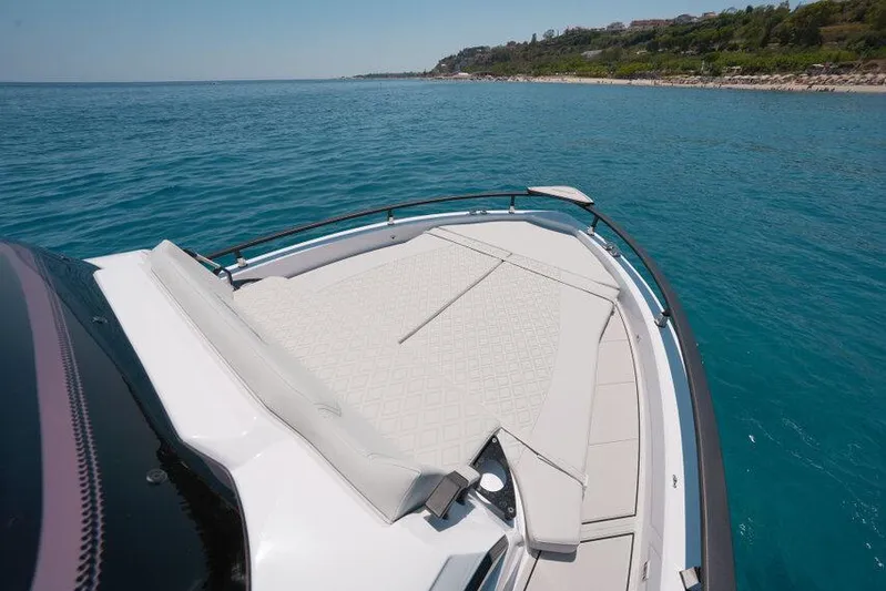  Yacht Photos Pics 2025 Ranieri NEXT 255 LX boat on clear blue water near a scenic coastline.