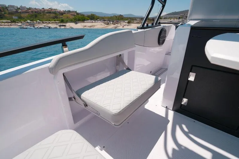  Yacht Photos Pics 2025 Ranieri NEXT 255 LX boat interior with foldable seat, near scenic coastline.