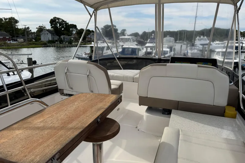 Blue Skies Yacht Photos Pics 2017 Regal 42 Fly yacht interior with white seating and wooden table, docked at marina.