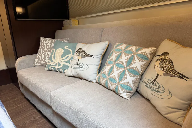 Blue Skies Yacht Photos Pics Beige sofa with decorative pillows featuring nautical and bird designs on a Regal 42 Fly yacht.