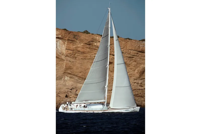 Polytropon II Yacht Photos Pics Swan 82 sailing yacht from 2008 by Nautor Swan, cruising near rocky coastline.