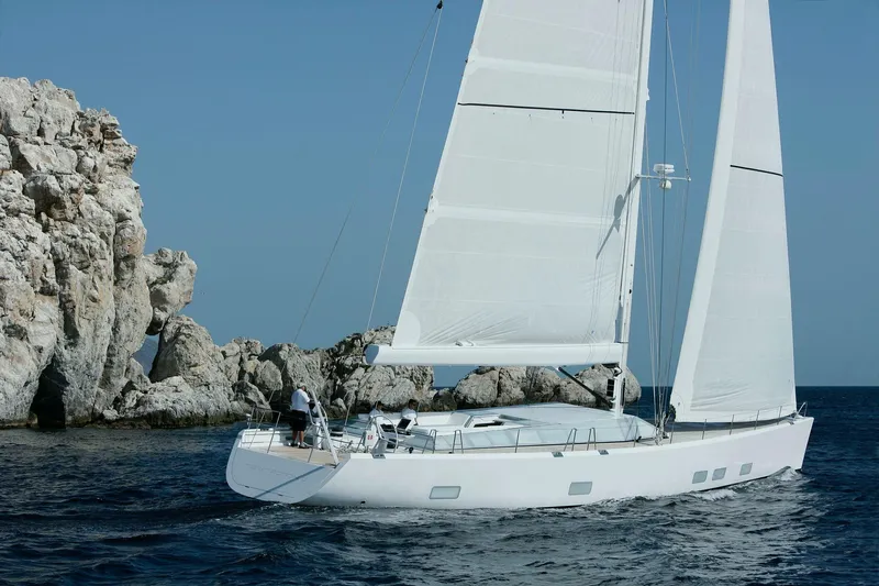Polytropon II Yacht Photos Pics Swan 82 yacht sailing near rocky coastline, clear blue sky, 2008 model.