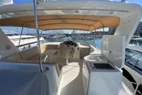 2011 Beneteau Swift Trawler 52 interior with helm, seating, and kitchenette under canopy.