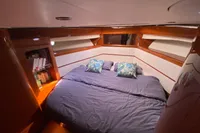 Luxurious cabin interior of 2011 Beneteau Swift Trawler 52 with cozy bedding and wooden accents.