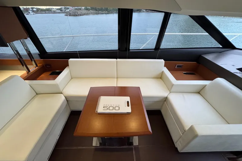  Yacht Photos Pics Luxurious interior of a 2013 Prestige 500 yacht with white seating and wooden table.