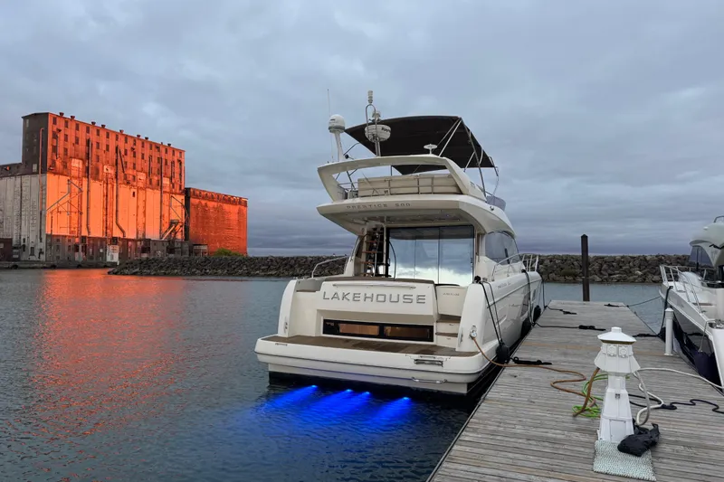  Yacht Photos Pics Luxury 2013 Prestige 500 yacht docked, illuminated by blue lights, with industrial building backdrop.