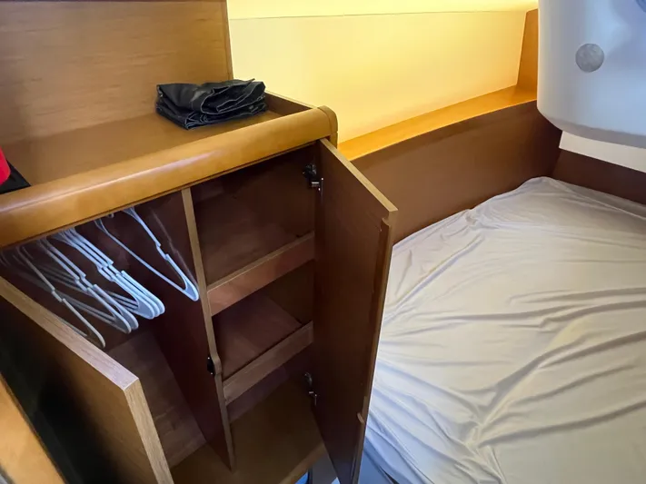 Venteux Yacht Photos Pics Interior of 2016 Jeanneau Sun Odyssey 349 showing cabin bed and wooden wardrobe with hangers.