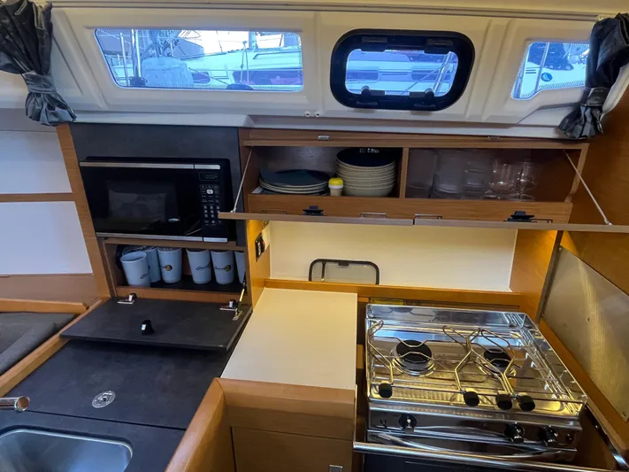 Venteux Yacht Photos Pics Compact kitchen in 2016 Jeanneau Sun Odyssey 349 sailboat with stove, microwave, and storage.
