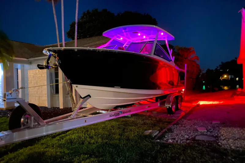  Yacht Photos Pics 2022 Blackfin 272DC boat on trailer, illuminated with vibrant red and purple lights at night.