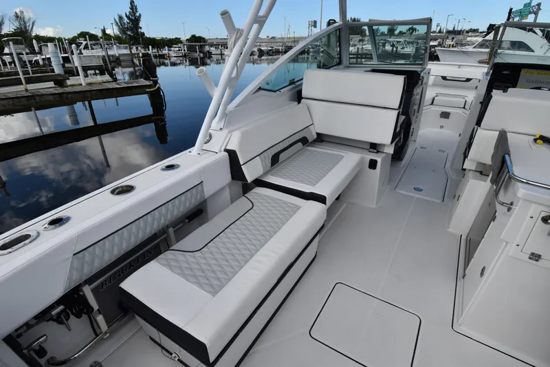  Yacht Photos Pics 2022 Blackfin 272DC boat interior with white seating and sleek design at a marina.