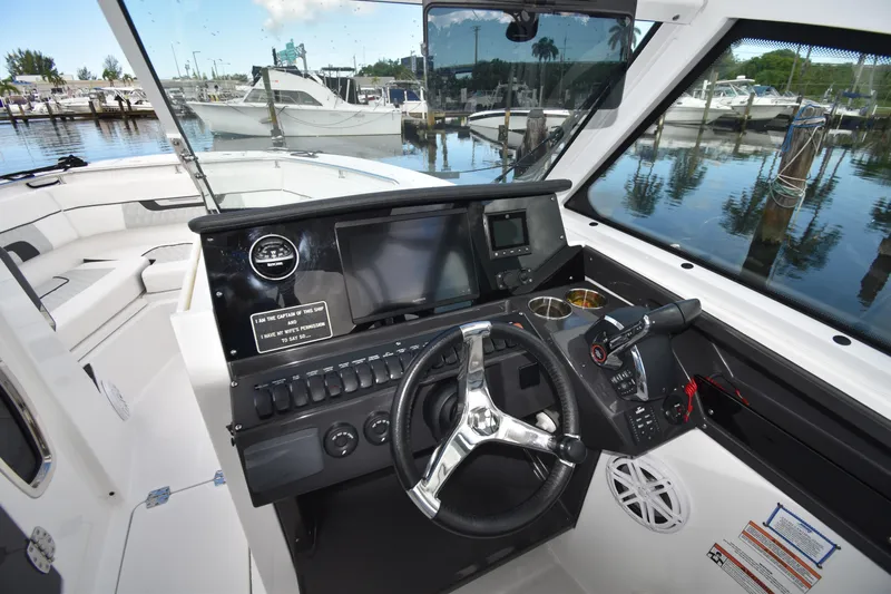 Yacht Photos Pics 2022 Blackfin 272DC boat cockpit with modern controls and marina view.