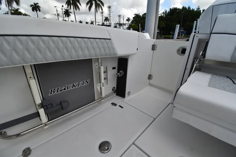  Yacht Photos Pics 2022 Blackfin 272DC boat interior with storage compartment and seating, palm trees in background.