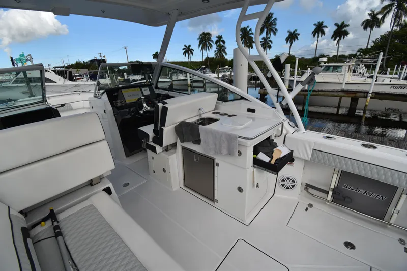  Yacht Photos Pics 2022 Blackfin 272DC boat interior with white seating and helm, docked near palm trees.