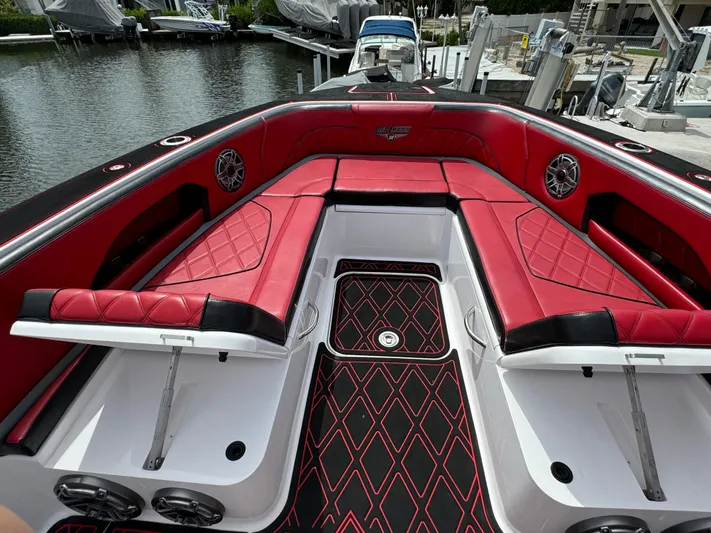  Yacht Photos Pics Luxurious 2022 Deep Impact 399 boat with red and black seating, docked by the water.
