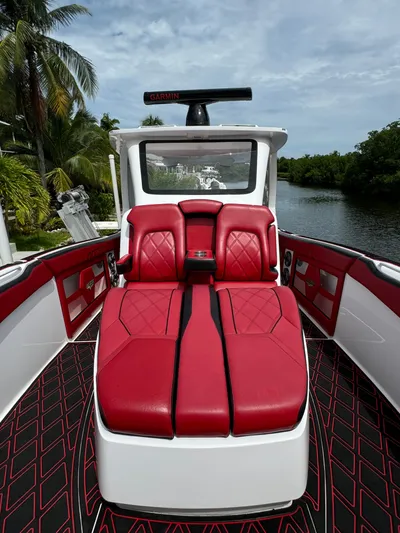  Yacht Photos Pics Luxurious 2022 Deep Impact 399 boat with red seating, docked by a scenic waterway.