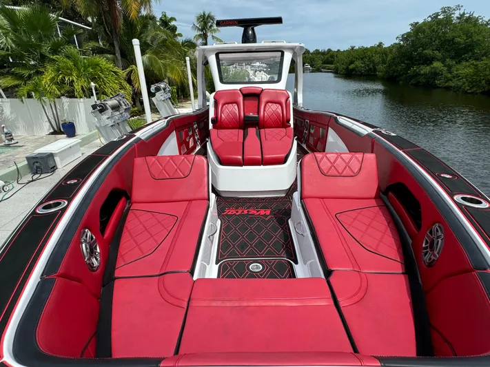  Yacht Photos Pics Luxurious 2022 Deep Impact 399 boat with red seating, docked by a scenic waterway.