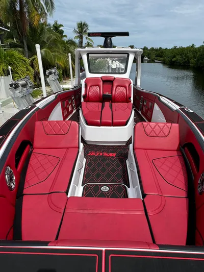  Yacht Photos Pics Luxurious 2022 Deep Impact 399 boat with red seating, docked by a scenic waterway.