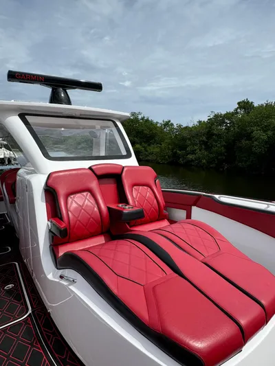  Yacht Photos Pics Luxury red seating on 2022 Deep Impact 399 boat, surrounded by lush greenery.