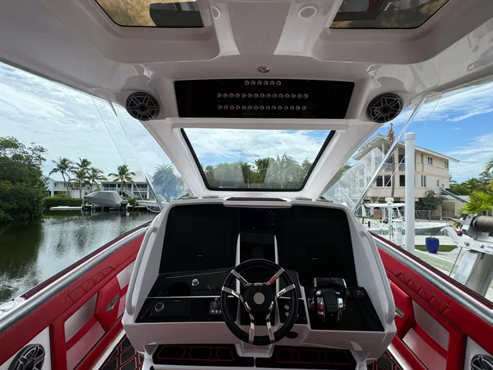  Yacht Photos Pics Interior view of 2022 Deep Impact 399 boat cockpit with red seating and modern controls.