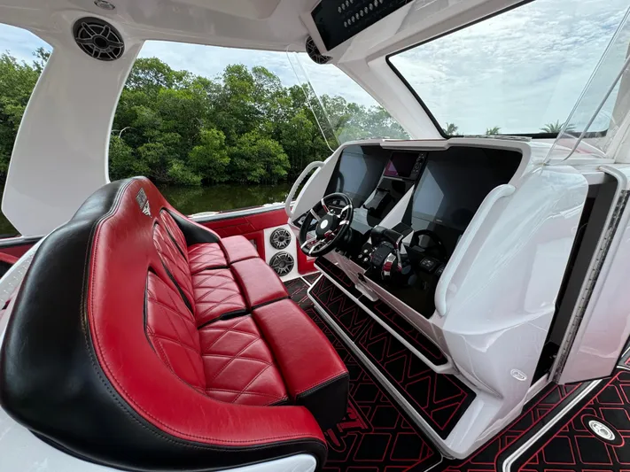  Yacht Photos Pics Luxury boat interior with red leather seats, modern dashboard, and scenic view. Deep Impact 399, 2022.