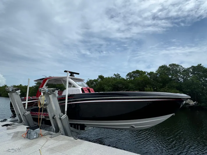  Yacht Photos Pics Deep Impact 399 boat, 2022 model, docked on a lift by a serene waterway.