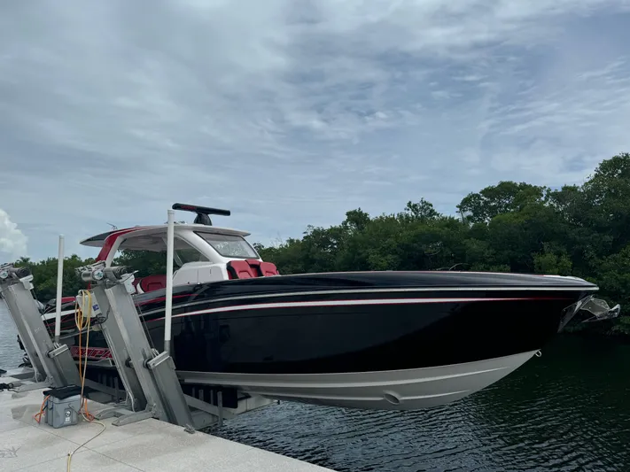  Yacht Photos Pics Deep Impact 399 boat, 2022 model, docked by lush greenery under a cloudy sky.