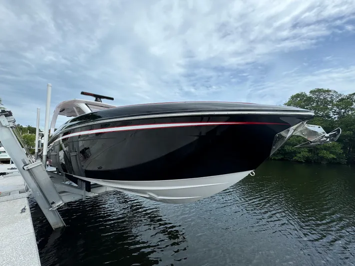  Yacht Photos Pics 2022 Deep Impact 399 boat on lift, sleek black design, cloudy sky background.
